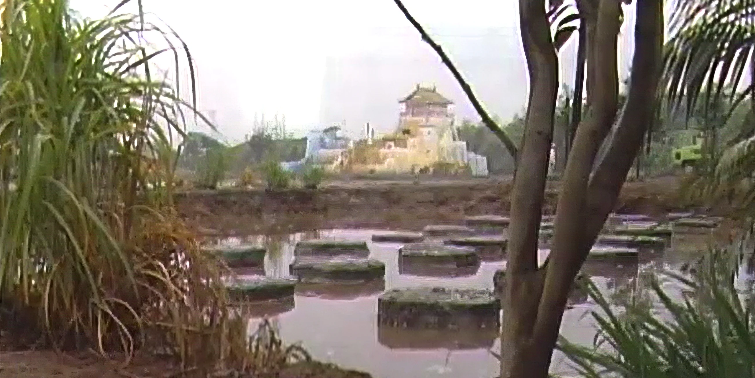 A low shot of a pond of steppping stones in the foreground and Takeshi's Castle in the distance